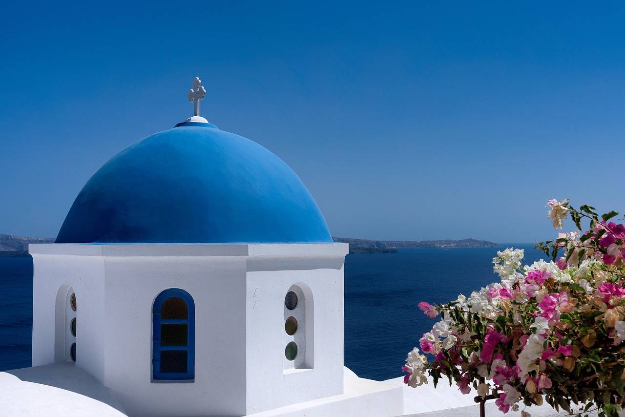 Bílý kostelík s modrou kupolí nad mořem na Santorini